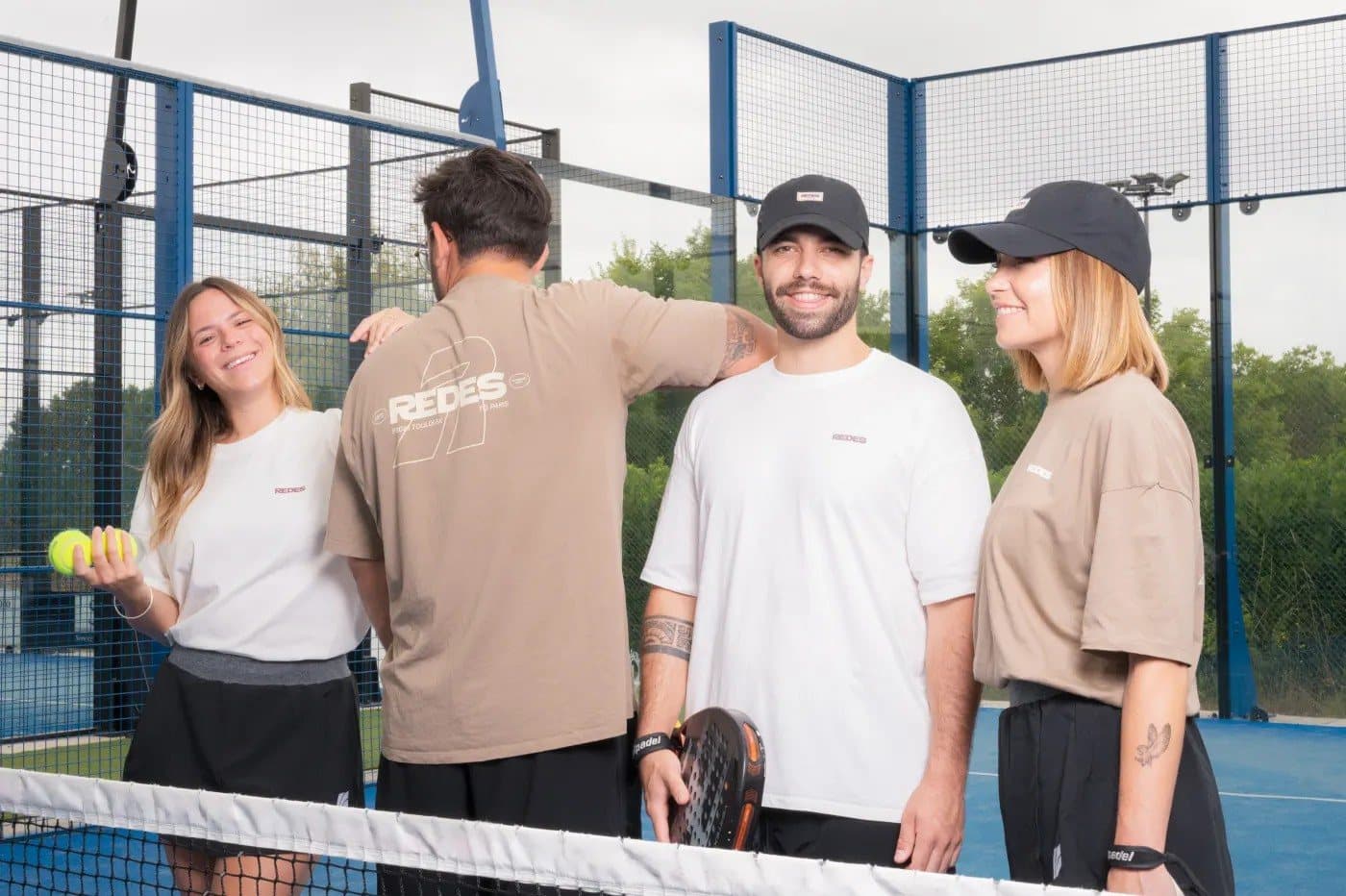 Quatre membres REDES en t-shirts du réseau sur un court de padel